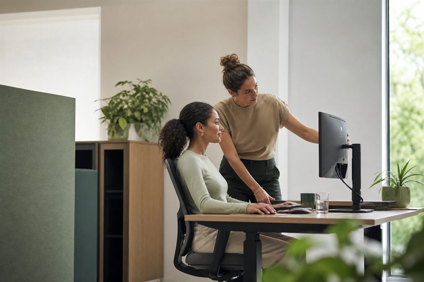 Adviseur bekijkt samen met een medewerker haar beeldschermwerkplek